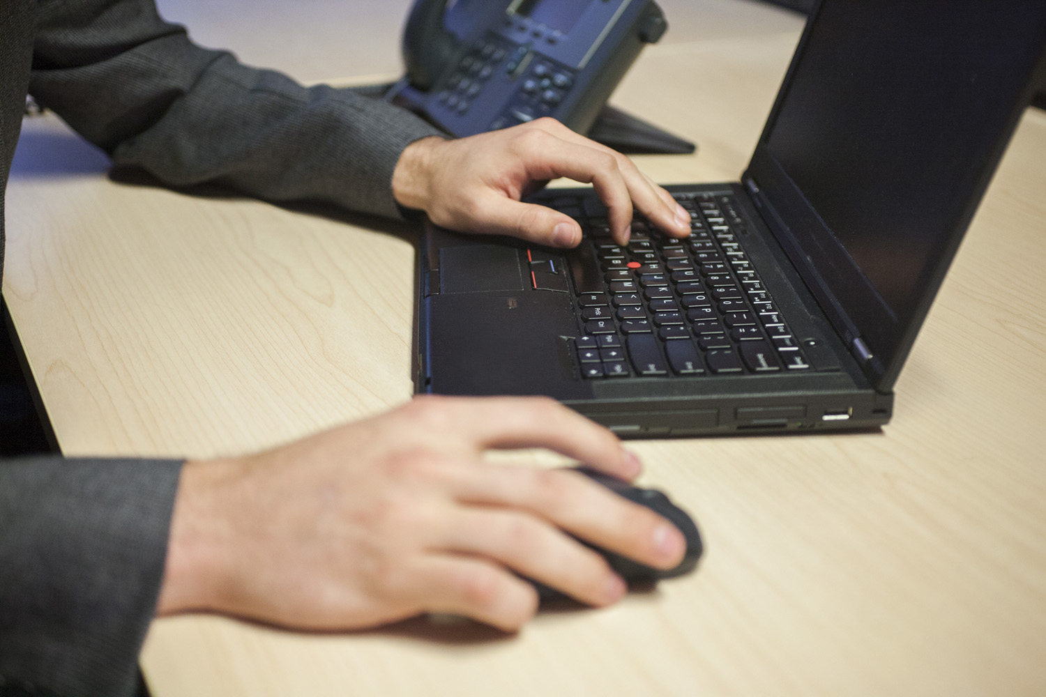 Person using laptop at desk with phone nearby.